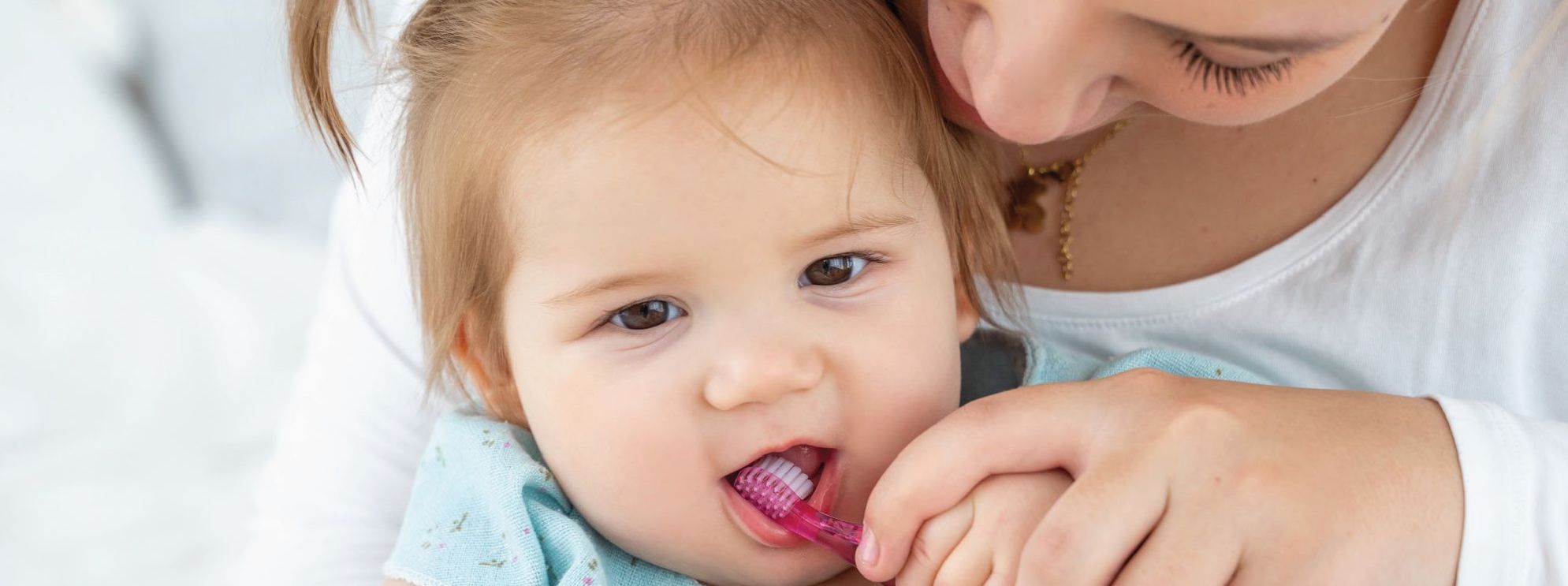 Mother brushing baby's teeth